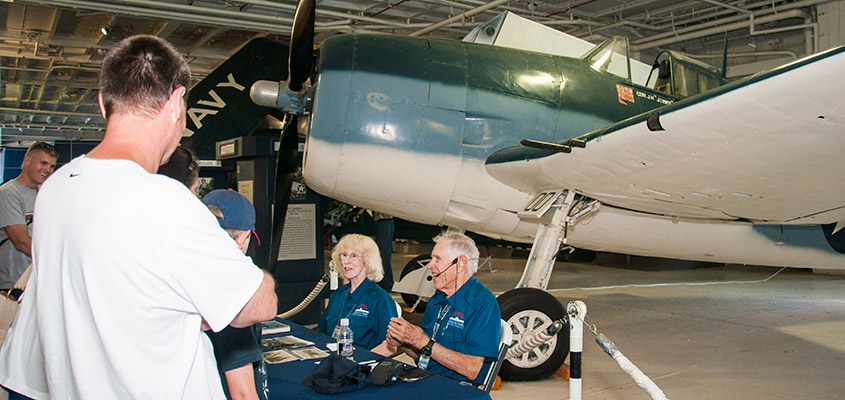 Fighter pilot Lt. Bill Watkinson flew the same aircraft Vice Admiral James Flatley Jr. did in WWII. Here he sits with Connie Reynolds answering questions in the USS Yorktown hanger. &copy; 2016 Audra L. Gibson.